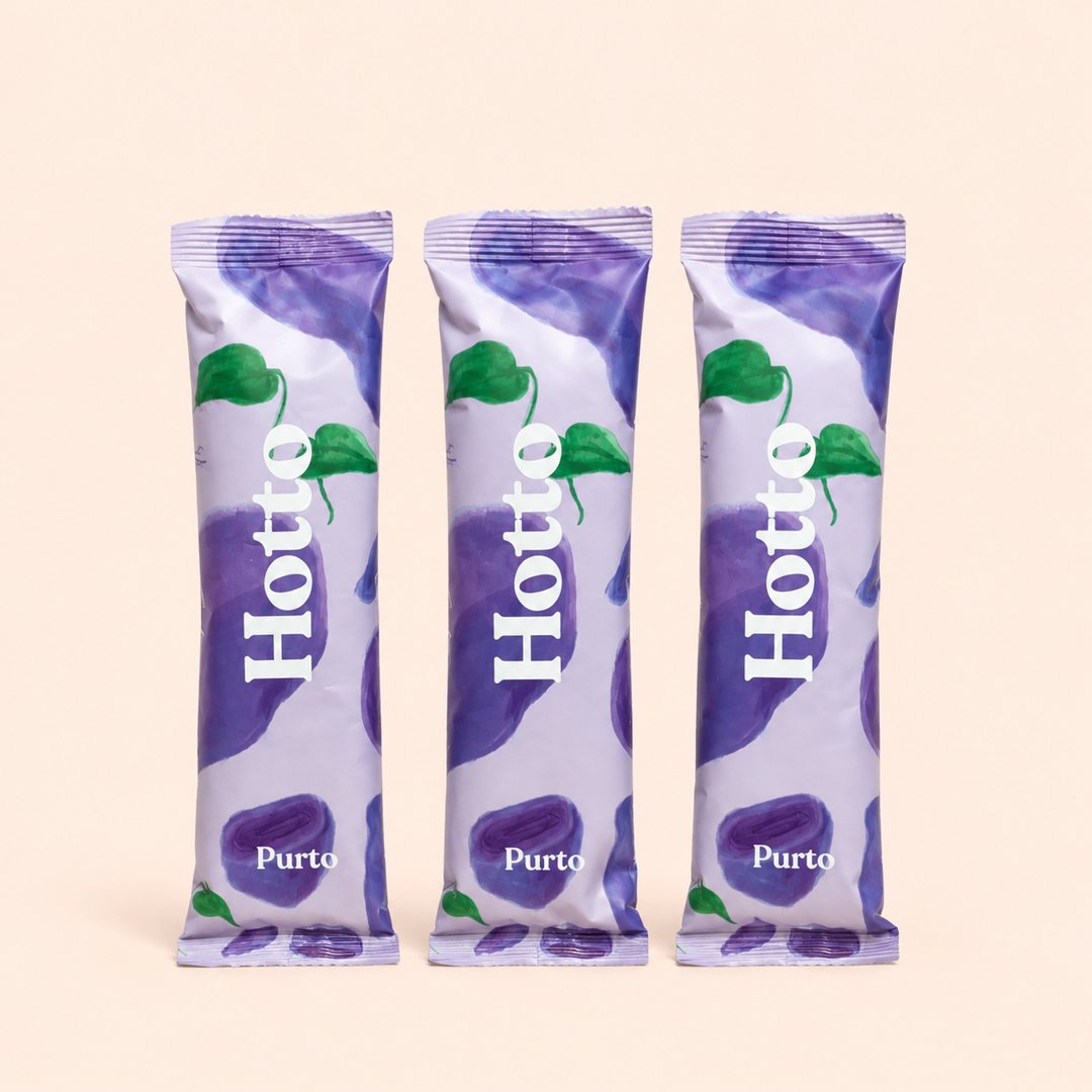Tiga sachet Hotto Purto Multigrain Oat Purple Potato dengan latar krem.